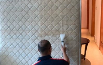 man with a vaccuum cleaning a white color mattress
