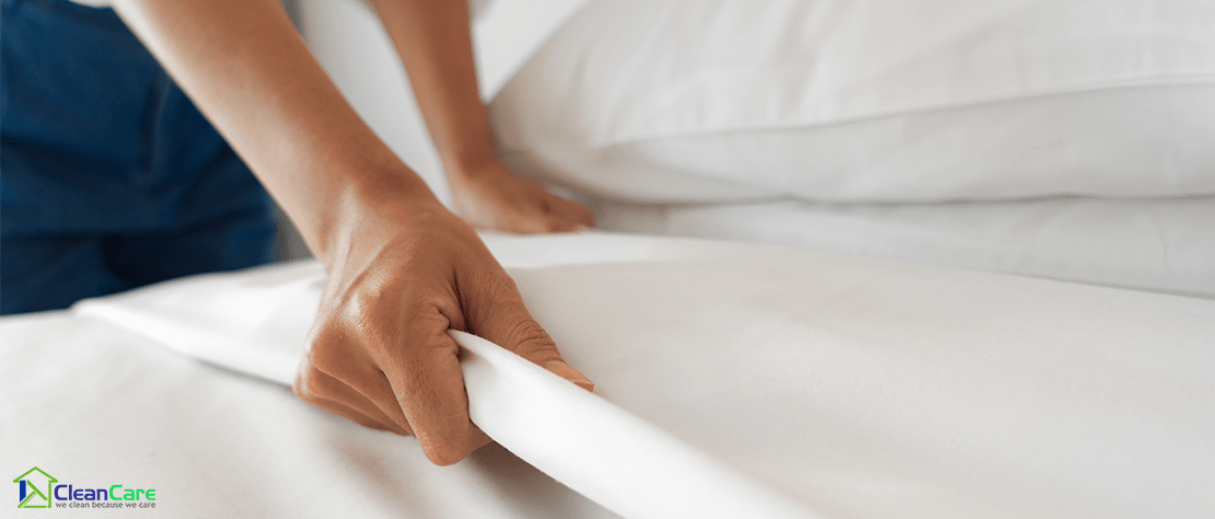 A person changing white mattress cover