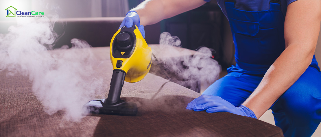 Professional using a steam cleaner on a couch.