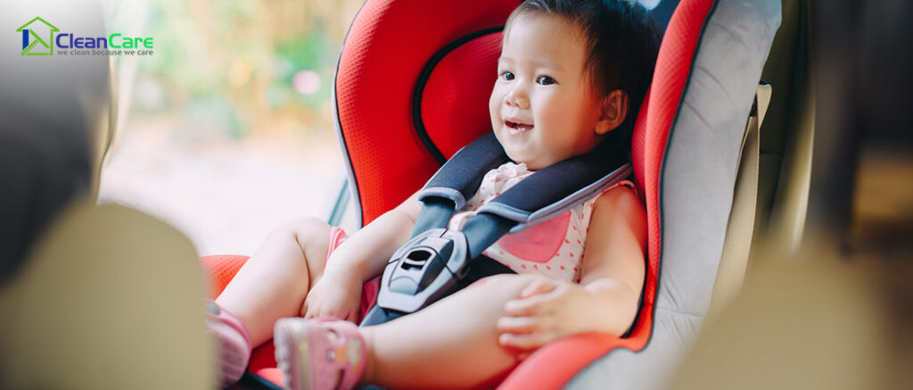A baby smiling while sitting in a car seat.
